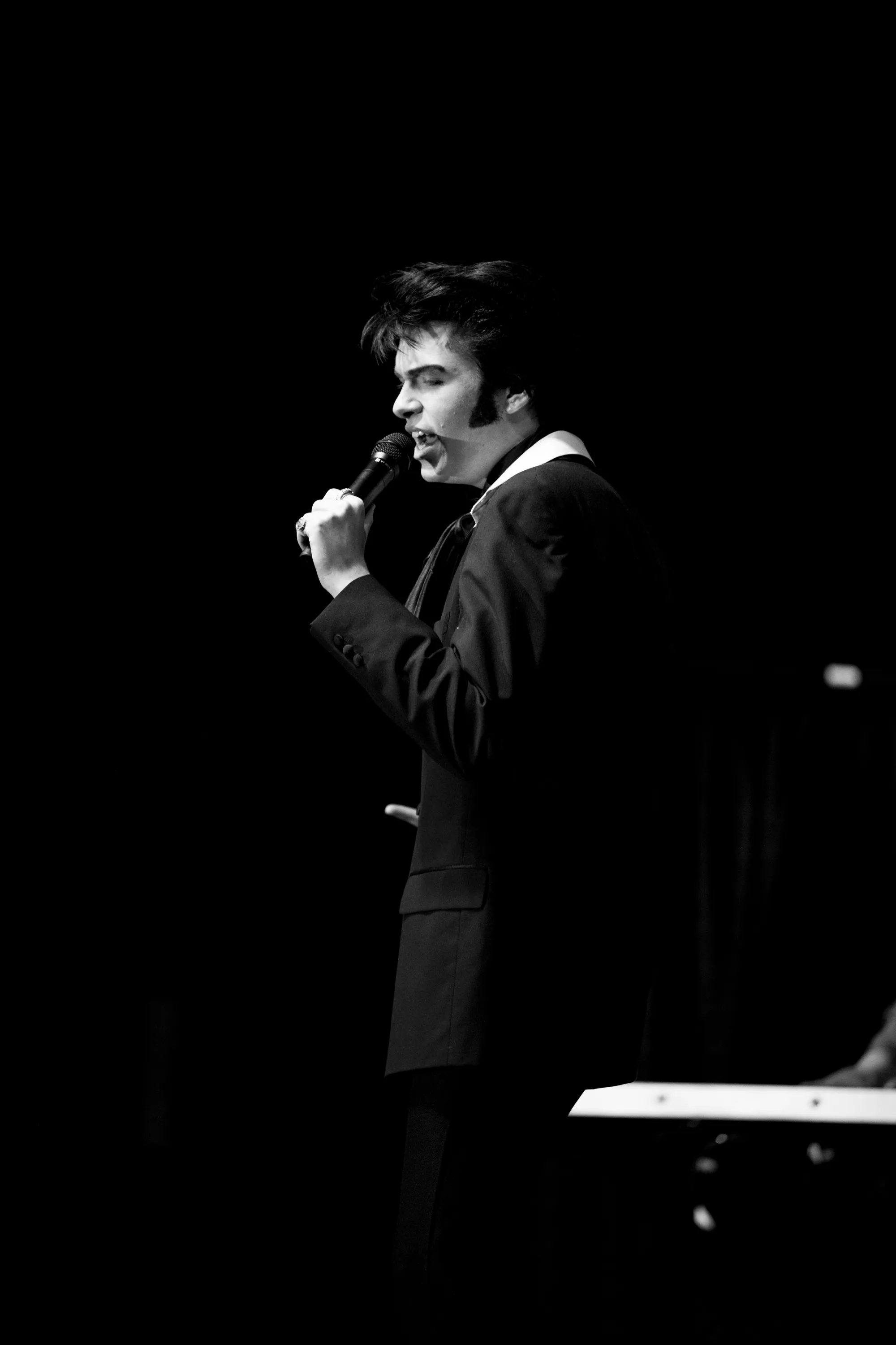 Finley Watkins singing into a microphone in a black suit
