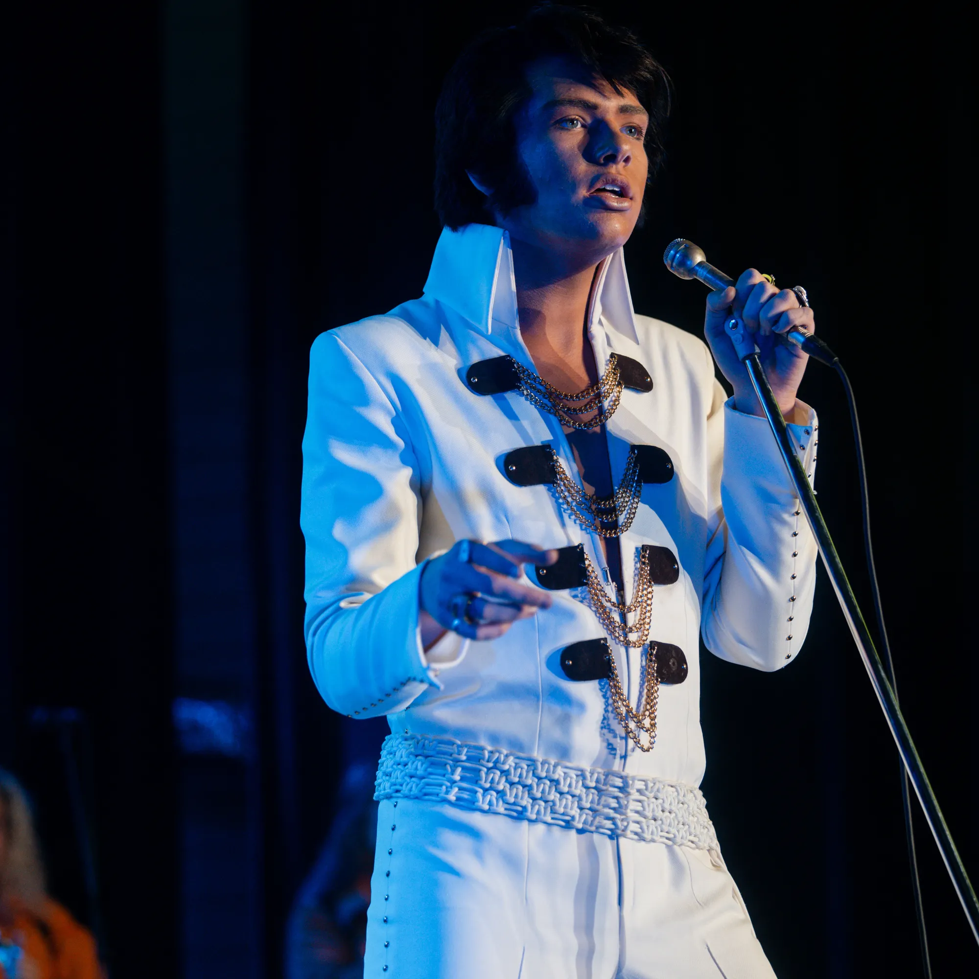 Finley Watkins singing on stage in a white Elvis tribute suit