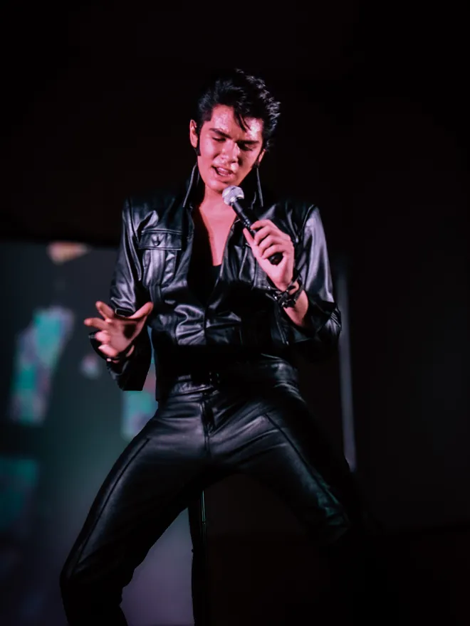 Finley Watkins performing in a black leather Elvis tribute outfit
